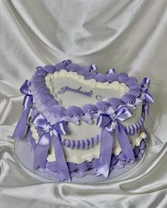 a heart shaped cake decorated with purple ribbons