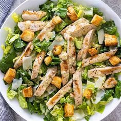 a salad with chicken and lettuce in a white bowl on top of a table