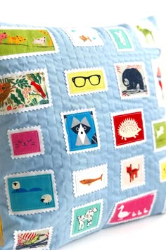 a blue pillow with various stickers on the front and back of it, sitting on a white surface