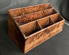 a wooden box that has compartments in it on a gray surface with a black background