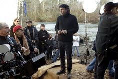 a group of people standing next to each other in front of a river with cameras