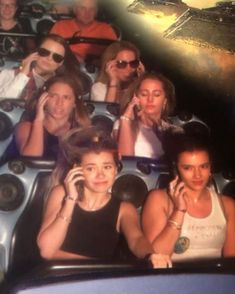 several people are sitting in a roller coaster talking on their cell phones