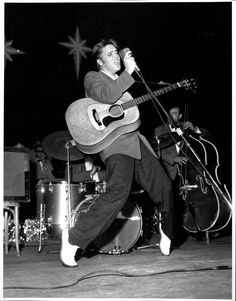 a man holding a guitar and singing into a microphone