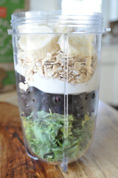 a blender filled with fruits and vegetables on top of a wooden table