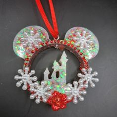 a mickey mouse ear ornament hanging from a red ribbon