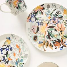 three plates and two cups with flowers painted on them