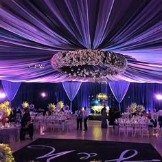 an elegant wedding reception with purple draping and chandelier draped over the dance floor