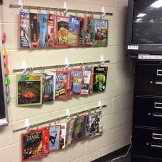 several magazines are hanging on the wall in front of a television and file cabinets with drawers