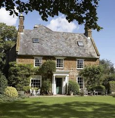 an old brick house with green lawn and trees