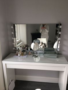 a white desk with a mirror and various items on it in front of a person taking a selfie