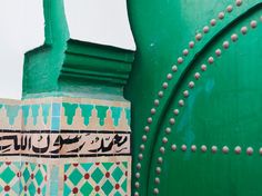 an ornate design on the side of a green building with metal studs and rivets