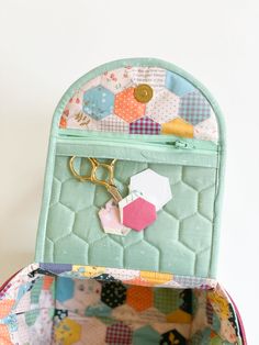 an open purse with scissors and patchwork material on the inside, in front of a white wall