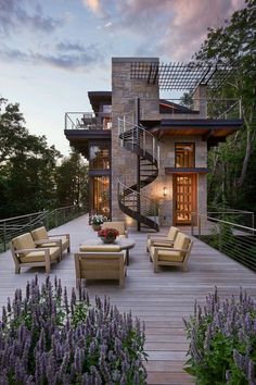 an outdoor living area with furniture and stairs leading to the upper floor, surrounded by lavender flowers