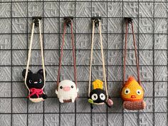 four small stuffed animals hanging from hooks on a wall