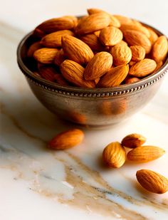 almonds in a metal bowl on a marble counter