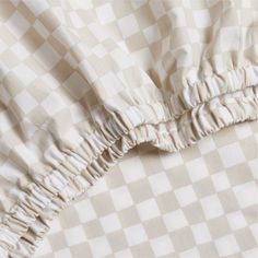 the fabric has ruffles on it in white and beige checkered pattern,