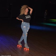 a woman riding roller skates on top of a wooden floor in a dark room