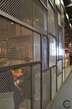 a man is walking down the sidewalk in front of a wall with metal mesh covering it