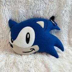 a stuffed animal that looks like a sonic the hedgehog is laying on a white blanket