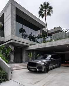 a black suv is parked in front of a modern house with palm trees and stairs