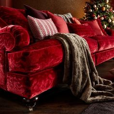 a red couch with christmas tree in the background