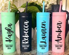 three different colored tumblers with the names of each one and two straws in them