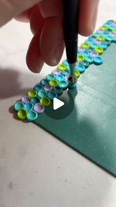 a person is using a pen to write on a piece of paper with colorful circles