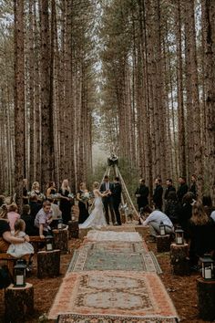 a couple getting married in the middle of a forest with lots of people around them