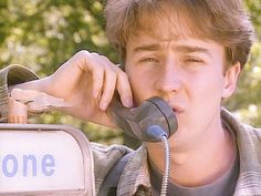 a young man talking on a phone next to a one way sign with the word gone written on it