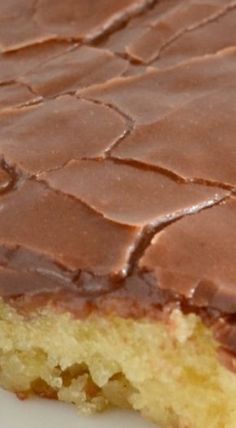 a close up of a piece of cake on a white plate with chocolate frosting