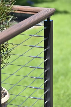 a potted plant sitting on top of a metal fence next to a green field