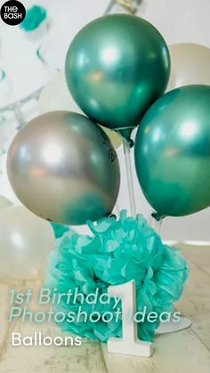 the first birthday photoshoot idea balloons are green and white with blue pom - poms