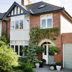 a large brick house with white trim and lots of greenery on the front door