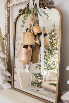 a mirror with bells hanging from it's sides and a christmas tree in the background