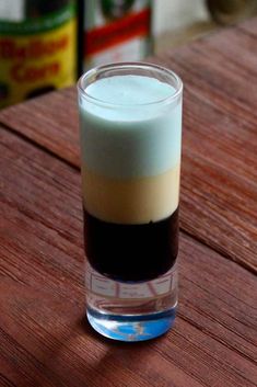 a glass filled with liquid sitting on top of a wooden table