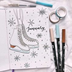 an open notebook with some pens and markers next to it on a white sheet covered in snowflakes