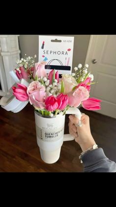 a person is holding a bouquet of flowers in a coffee cup with the name sephora on it