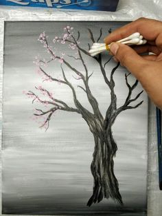 someone is painting a tree with white and pink flowers