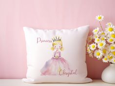 a white pillow with a princess on it next to flowers and a vase filled with daisies