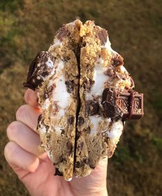 a person holding up an ice cream sandwich with chocolate chips and marshmallows