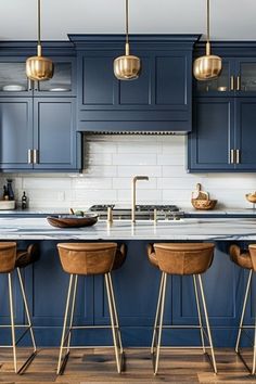 an image of a kitchen setting with blue cabinets and bar stools in the center