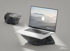 an apple laptop sitting on top of a rock next to a piece of stone that has been placed in front of it