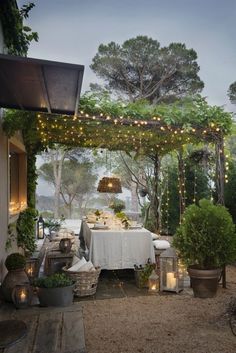 an outdoor dining area is lit up with fairy lights