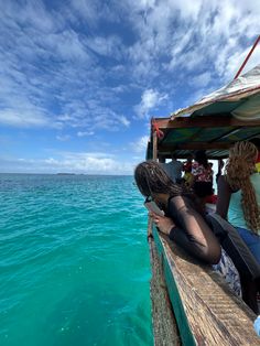 two women are sitting on the edge of a boat looking at something in the water