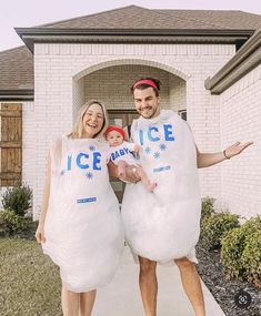 a man and woman dressed up as ice babies in front of a white brick house