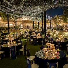 tables and chairs are set up in the middle of an outdoor venue with lights strung from the ceiling