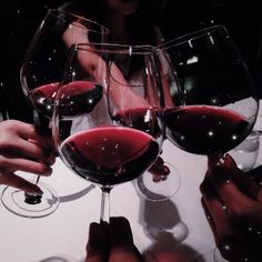 several people holding wine glasses with red wine in them