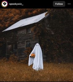 a ghost with a pumpkin in his hand is standing in front of an old house