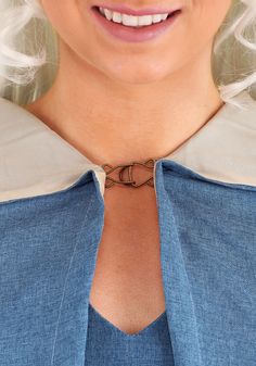 a woman with white hair wearing a blue shirt and a silver tie around her neck