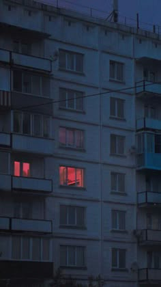 an apartment building with red light coming from the windows